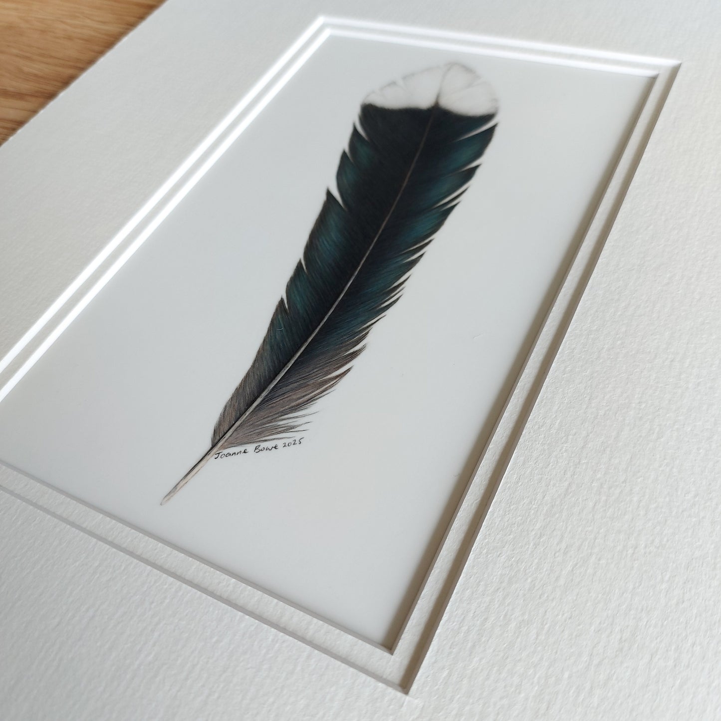 Angled view of the original huia feather artwork, showing surface texture and tonal depth.