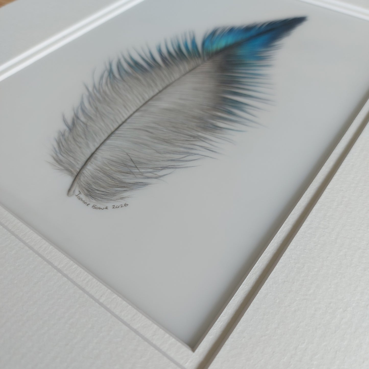 Angled view of the original tūī feather artwork, showing surface texture and depth.