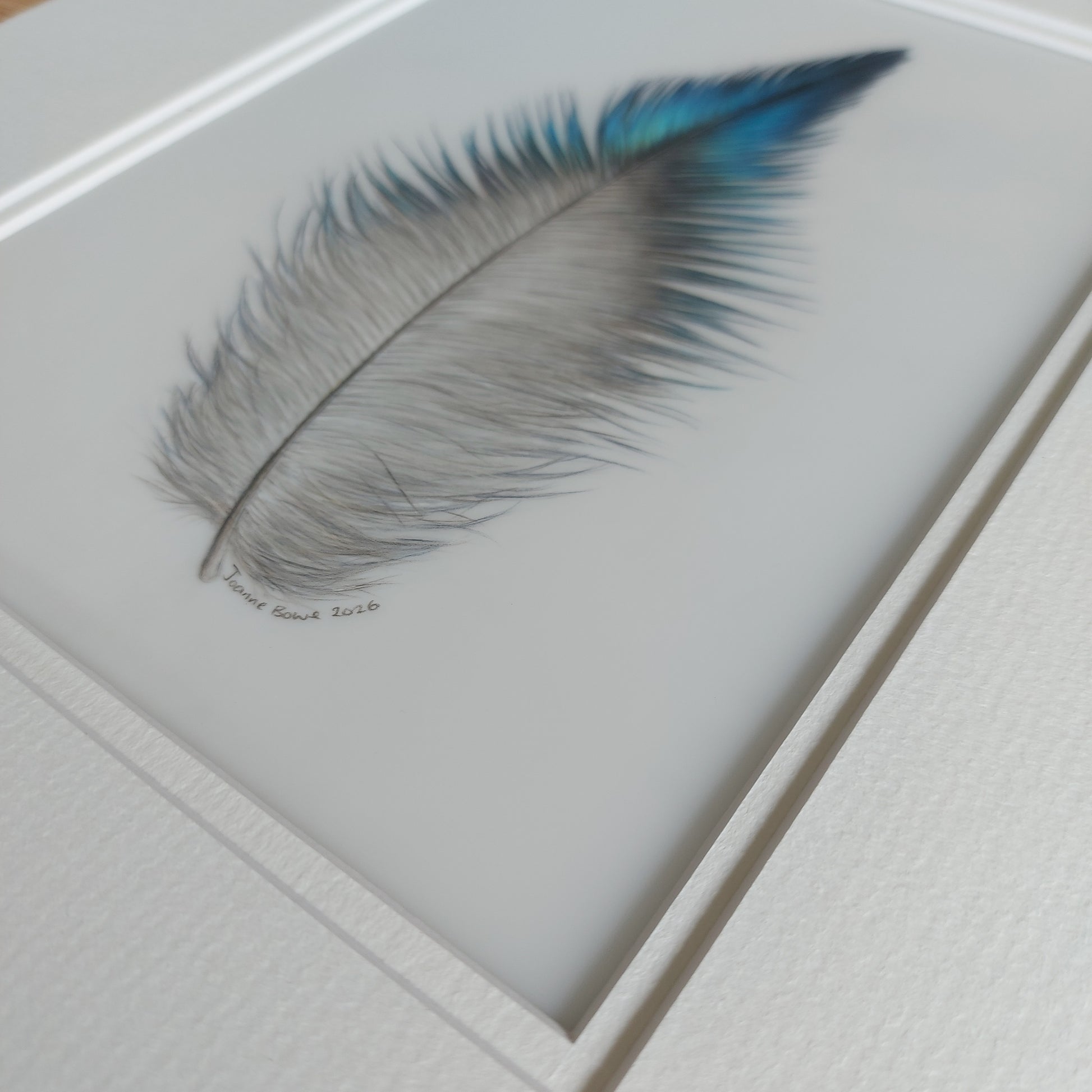 Angled view of the original tūī feather artwork, showing surface texture and depth.